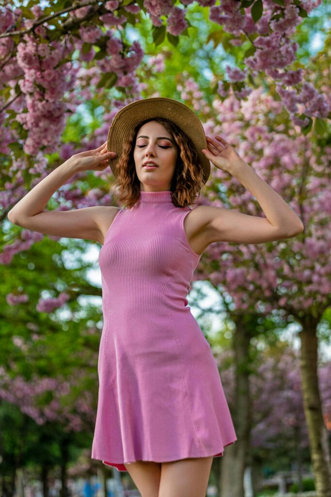 A woman in a pink dress stands serenely among blooming cherry blossoms in Istanbul.